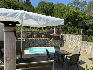 a patio with an umbrella and a swimming pool at Christina Apartment in Mesochórion