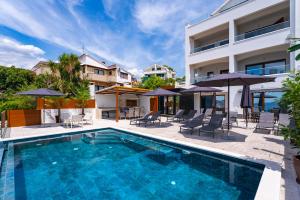 una piscina con sedie e ombrelloni accanto a un edificio di Villa Paladium a Trogir