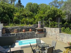 a backyard with a swimming pool and a stone wall at Christina Apartment in Mesochórion