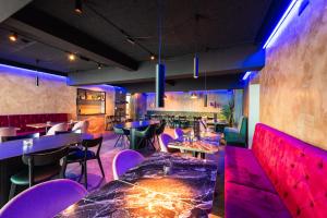 a restaurant with purple chairs and tables and a bar at Centrum Hotel in Akureyri