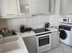 eine Küche mit weißen Schränken und einer Waschmaschine und einem Trockner in der Unterkunft ZenPoint in Larisa + 11 Fotos
