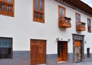 a white building with wooden doors and windows at Nodo Cusco Garcilaso in Cusco