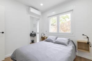 a white bedroom with a bed and a window at Aptos Ría San Cosme Aurora in Bendimón