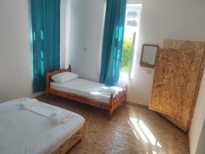 a room with two beds and a window with blue curtains at Guest house Lori in Pogradec +30 photos