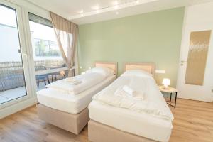 two white beds in a room with a balcony at Theresa - Penthouse Terrasse Klima Parkplatz in Fellbach