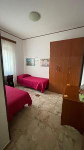a bedroom with two red beds and a cabinet at Brezza Marina in Gallico