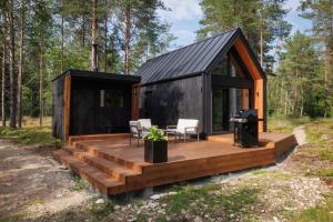a black and wooden cabin with a deck and a grill at Keibulahe Puhkemaja in Keibu