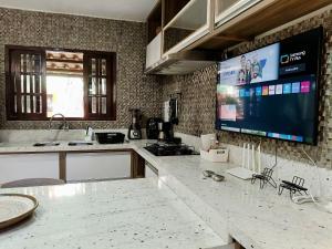 una cucina con una grande TV a parete di Colibri - Conforto e Vista-Mar no Coração de Pipa a Pipa