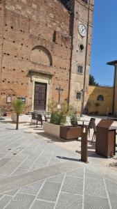 a building with a clock tower with tables and chairs at Elena & Leila in Santa Maria a Monte