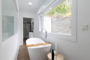 a bathroom with a white tub and a window at Aptos Ría de San Cosme María in Bendimón +27 photos