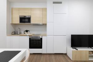 a kitchen with white cabinets and a flat screen tv at Aptos Ría de San Cosme María in Bendimón