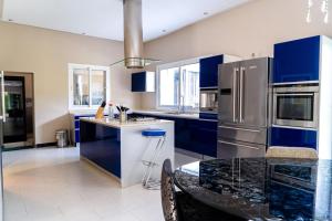 Una cocina con gabinetes azules y un refrigerador de acero inoxidable. en Bouskoura park, en Bouskoura
