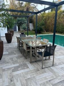 Un patio con mesa y sillas y una piscina. en Bouskoura park, en Bouskoura