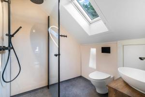a bathroom with a toilet and a sink and a skylight at Kongshamn Gjestgiveri in Kirkehamn +37 photos