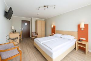 a bedroom with a large white bed and a desk at Atomis Hotel Düsseldorf City in Düsseldorf