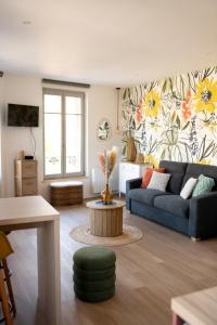 ein Wohnzimmer mit einem blauen Sofa und einem Blumenbild in der Unterkunft Studio Lucien - Villa Bon Accueil proche mer in Mers-les-Bains