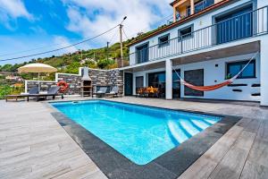a villa with a swimming pool with a hammock at Villa da Bisa with heated swiming pool in Arco da Calheta