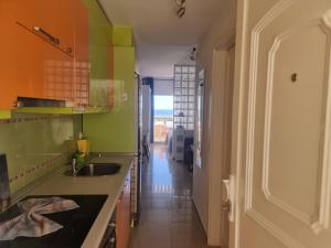 a kitchen with green walls and a sink and a hallway at Apartamento Ura in Morro del Jable +11 photos
