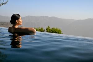 a woman sitting in a pool in the water at Hotel Indigo Jabal Akhdar Resort & Spa by IHG in Al ‘Aqar