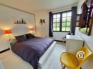 a bedroom with a large bed and a yellow chair at Millésime in Saint-Jean-sur-Mayenne