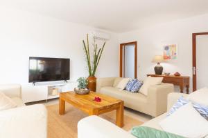 a living room with white furniture and a tv at Chalet Muro en Mallorca in Playa de Muro