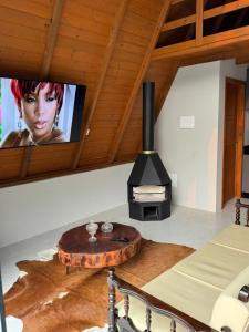 a living room with a wood stove and a tv at Chalé Dovale in Sambaqui