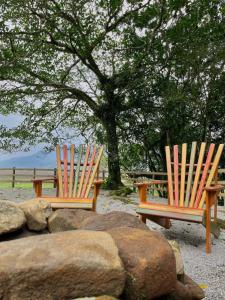 two wooden chairs sitting in front of a tree at Chalé Dovale in Sambaqui