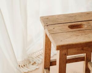 a wooden table with a wooden stool next to a window at Alpenrose in Obermaiselstein