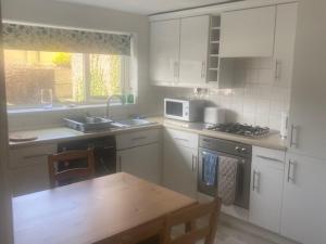 una cucina con mobili bianchi, un tavolo e un microonde di Town centre flat near harbour attractions and restaurants a Maryport