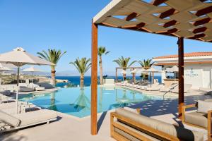 a swimming pool with chairs and umbrellas at Iberostar Waves Creta Panorama & Mare in Panormos Rethymno