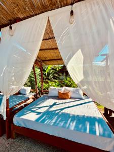 two beds under a roof with a canopy at On Board Lifestyle Resort FREE MOTORBIKE in Bil-isan