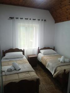 two beds in a room with a window at Bujtina Milani in Theth