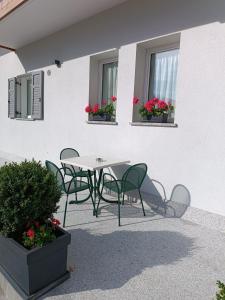 a table and chairs in front of a building with flowers at Casa Nadia - Val di Sole Apartment in Piano
