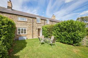 une maison avec une table et des chaises dans la cour dans l'établissement Host & Stay - Dove Cottage, à Warkworth