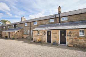 une rangée de bâtiments en briques avec des portes et des fenêtres dans l'établissement Host & Stay - Dove Cottage, à Warkworth