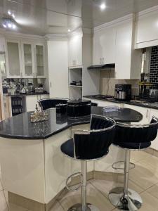 une cuisine avec des comptoirs noirs et des tabourets de bar dans l'établissement Estelle Family cottage, à Johannesbourg