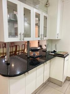 une cuisine avec des armoires blanches et un comptoir noir dans l'établissement Estelle Family cottage, à Johannesbourg