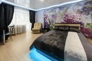 チェリャビンスクにあるInnHome Apartments Plekhanova Street 14のベッドルーム1室(ベッド1台付)と花の壁画が備わります。