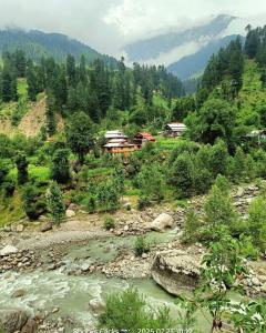 un gruppo di case su una collina vicino a un fiume di Ibex Riverside Cottage Neelum Valley a Kundālshai