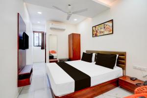 a bedroom with a large bed and a television at Hotel O Railway in Vadodara
