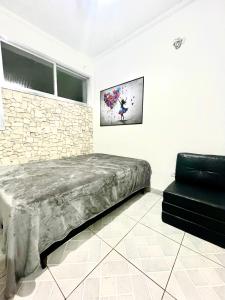 a bedroom with a bed and a chair in it at Linda Kitinete frente a praia in São Vicente