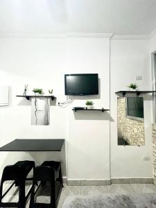 a living room with a tv on a white wall at Linda Kitinete frente a praia in São Vicente