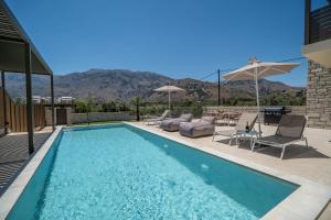 una piscina con sedie e ombrelloni in una casa di Villa Zen Aphrodite by PosarelliVillas a Asprouliánoi