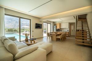 un soggiorno con un divano, un tavolo e una cucina di Villa Zen Aphrodite by PosarelliVillas a Asprouliánoi