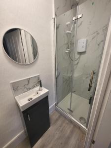 a bathroom with a shower and a sink and a mirror at 43 Deluxe London Ensuites in London