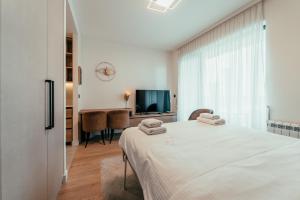 a white bedroom with a bed and a television at BW Symphony Suites in Belgrade