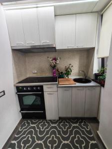 a kitchen with white cabinets and a stove and a sink at Vila Bella in Văleni