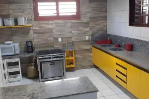 eine Küche mit einem Herd und gelben Schränken in der Unterkunft Mansão14Suítes-55Pessoas-BEACH PARK - HOUSINGCEARÁ in Aquiraz
