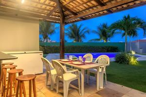 eine Terrasse mit Tisch und Stühlen unter einer Pergola in der Unterkunft Mansão Luxo 32 Pessoas-BeachPARK - BY HousingCeara in Aquiraz