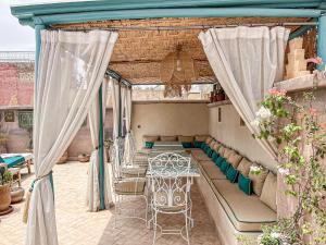 a patio with a table and chairs and curtains at Riad Jamaique - Marrakech in Marrakesh